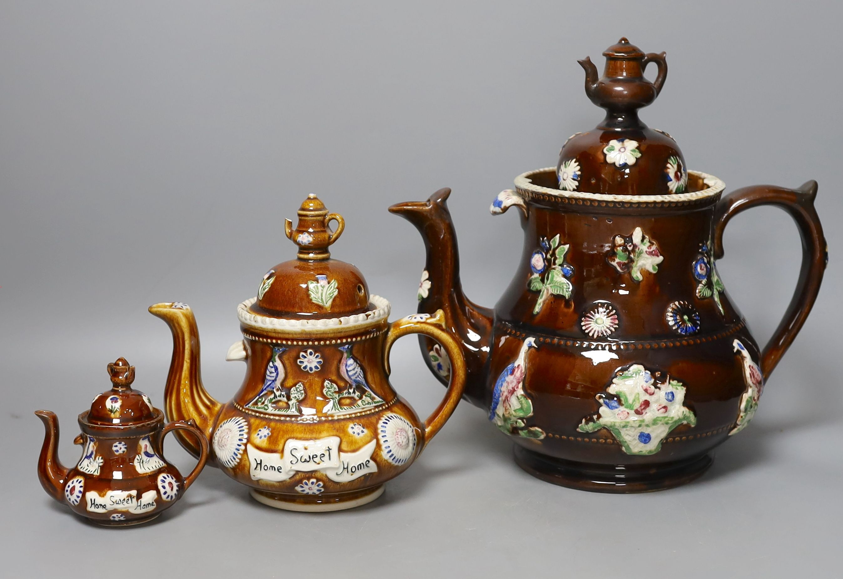 A Victorian Measham Bargeware pottery tea pot and cover, 29cm high and two similar reproduction teapots